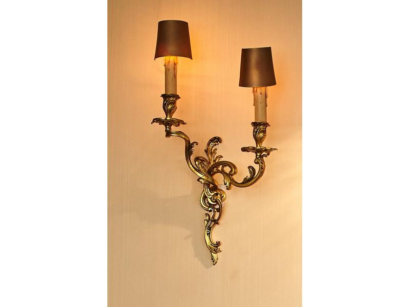SUITE DE SIX APPLIQUES en bronze à deux lumières...