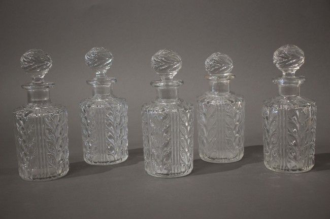 CINQ FLACONS en verre moulé à décor de feuillage...