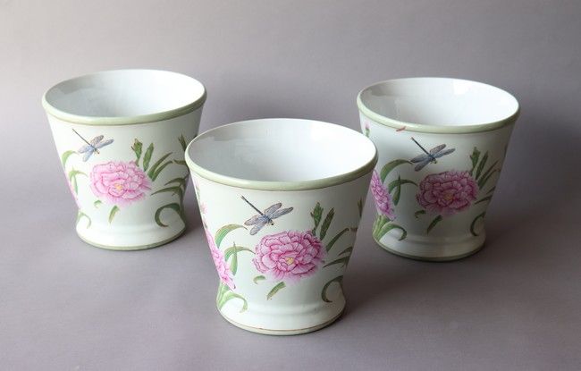 TROIS CACHE-POTS ronds en porcelaine polychrome...