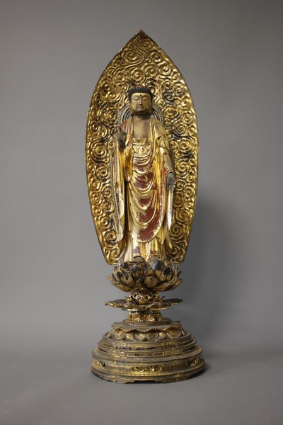 BOUDDHA en bois sculpté debout devant une...