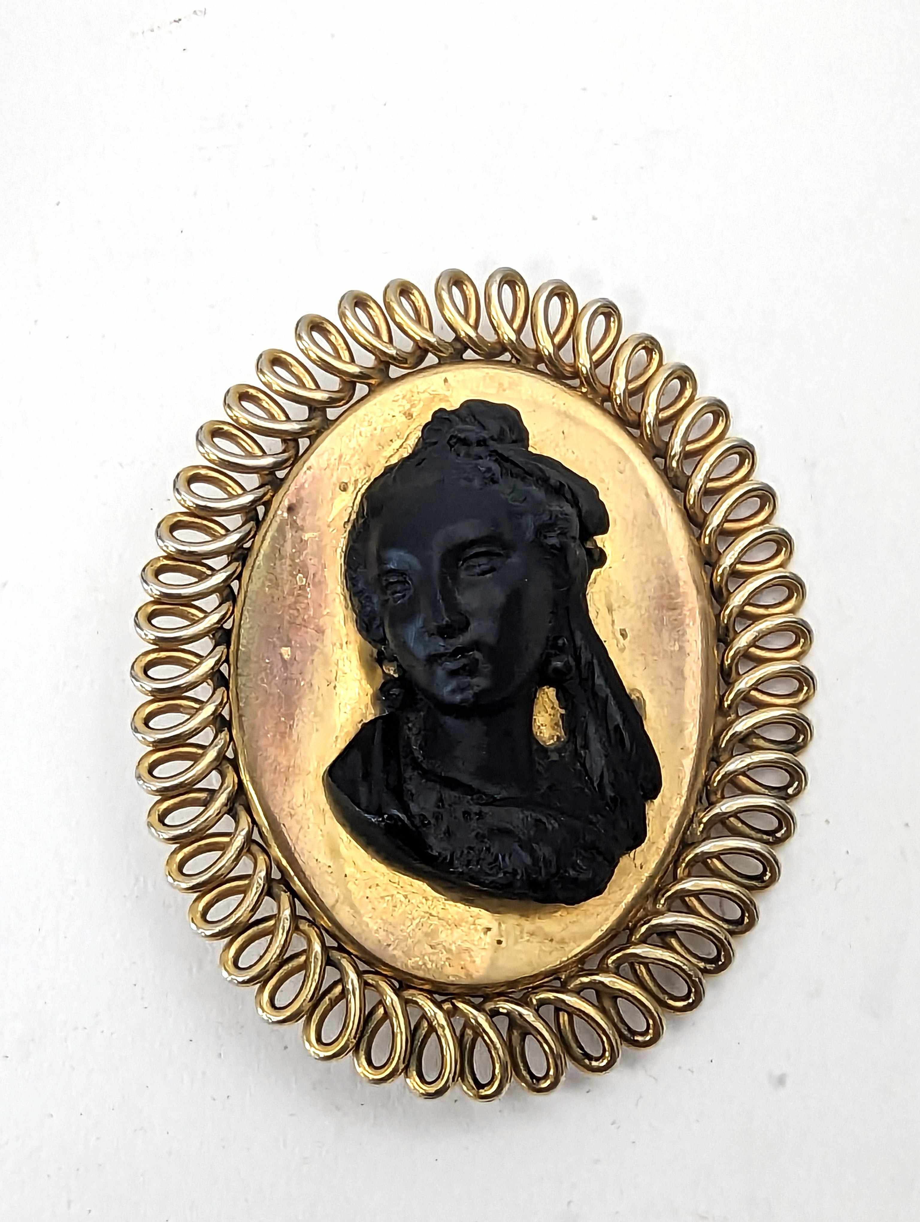 BROCHE ovale en métal doré centrée d'un buste...