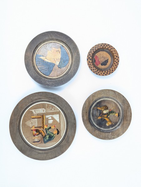 QUATRE ASSIETTES ou MÉDAILLONS en bois pyrogravé...