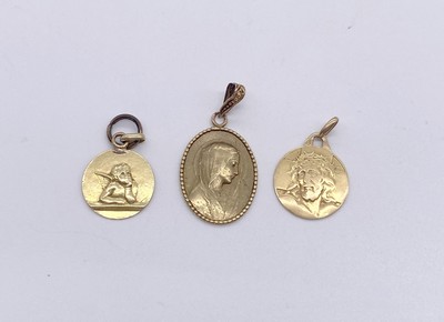 TROIS MÉDAILLES en or (750). Un anneau en...