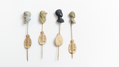 QUATRE ÉPINGLES DE CRAVATE en métal sommées...